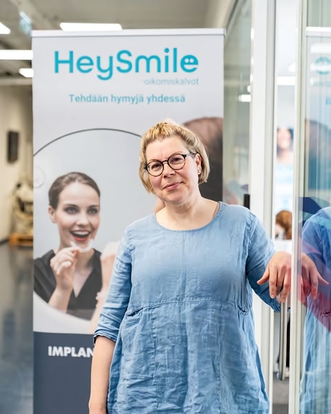 This ad creative features a professional dental brand representative standing next to a pull-up banner displaying a happy customer using dental aligners.